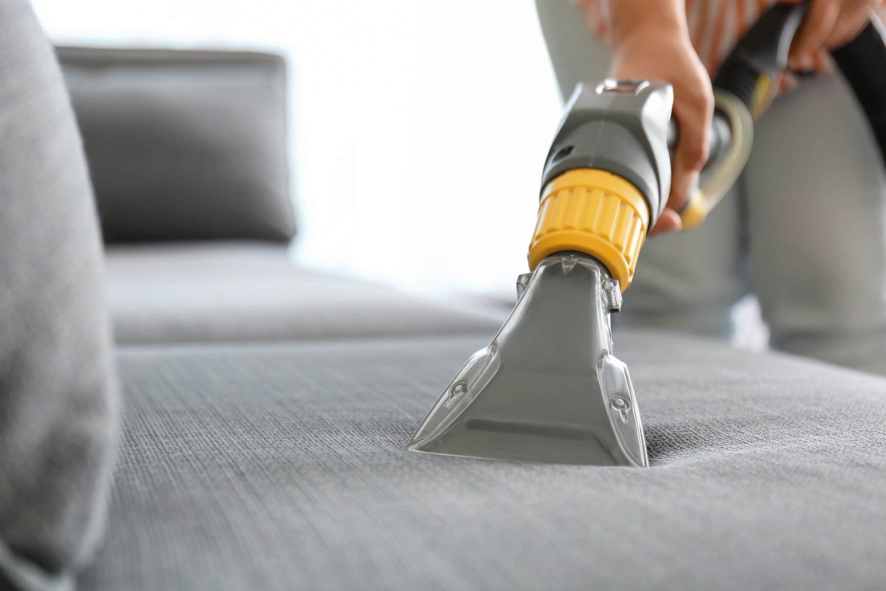 Woman Removing Dirt from Sofa at Home